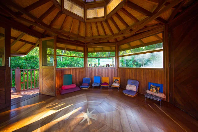 Sunlit wood meditation pavilion surrounded by tropical greenery at KMEC Hawaii